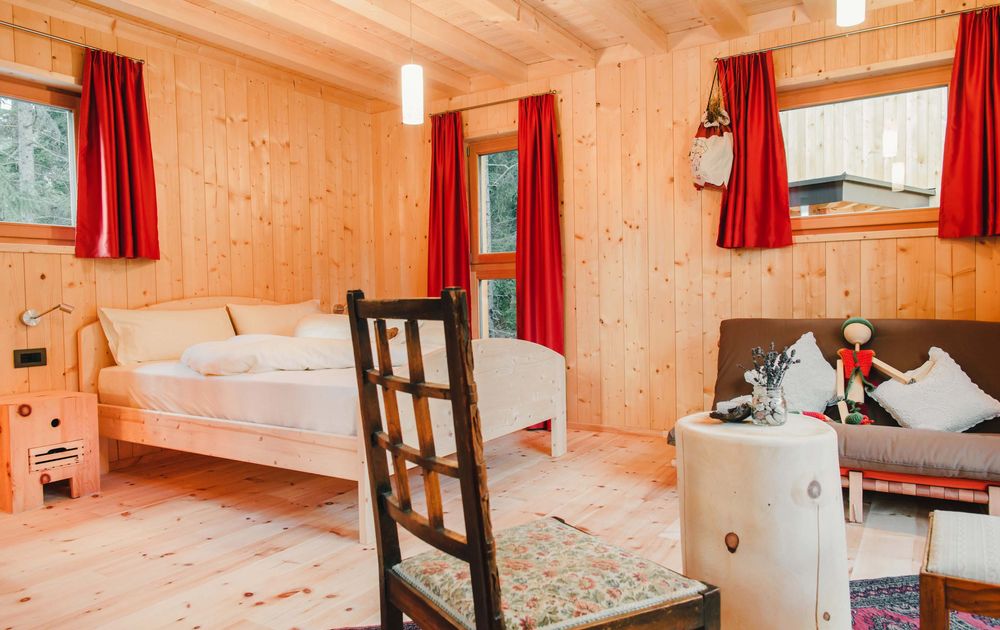 Schlafzimmer mit Doppelbett und Sofa im Chalet UNO feliZitas Forest Chalet Holidays Südtirol